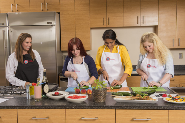 woman and three college age girls cooking